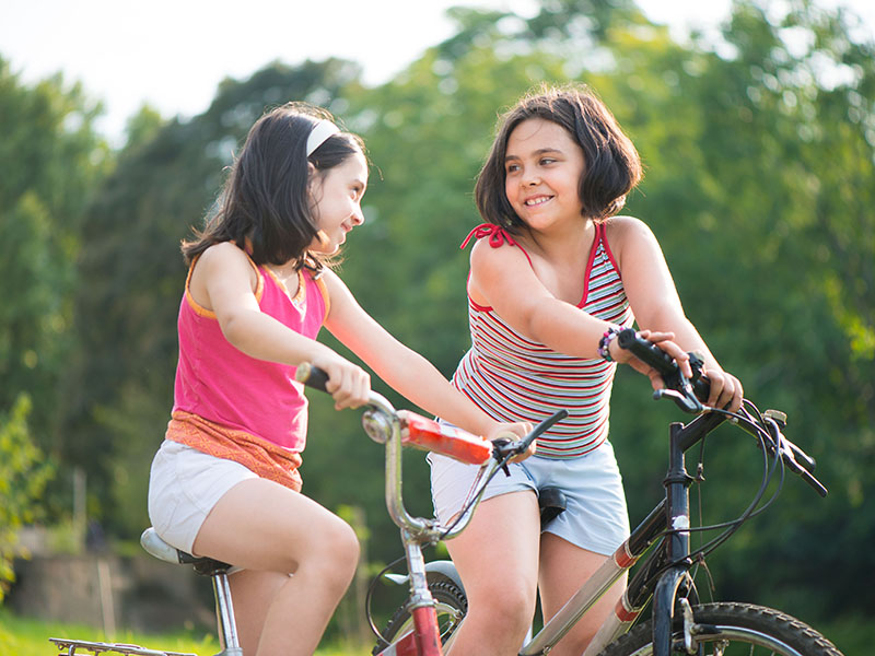 Two,Pretty,Hispanic,Children,Riding,On,Their,Bikes