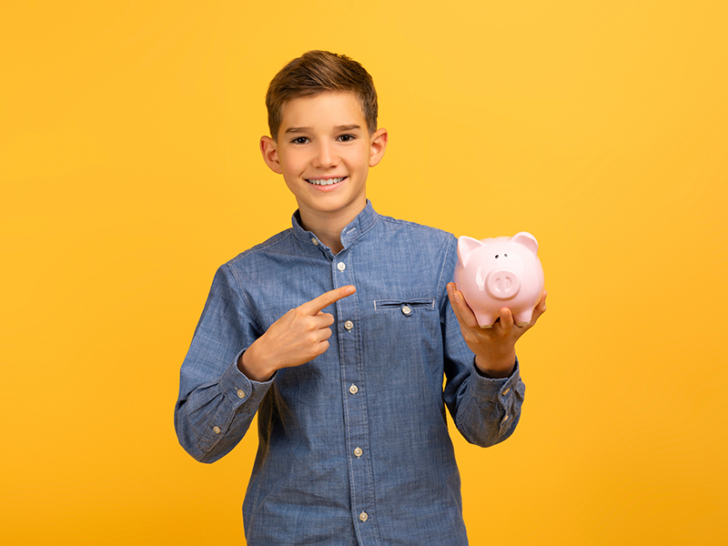 Happy,Excited,Teen,Boy,Pointing,At,Piggy,Bank,And,Looking