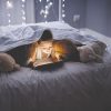 Tablet, reading and kid at night with video, story and youth game with fantasy and language learning app. Tech, teddy bear and young girl with scroll, relax and evening at home in bed on internet