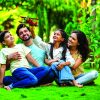 Joyful Indian couple with their kids sitting in a park, embracing each other and admiring a toy plane held by their daughter, symbolizing love, family time, imagination, and togetherness, aspiration