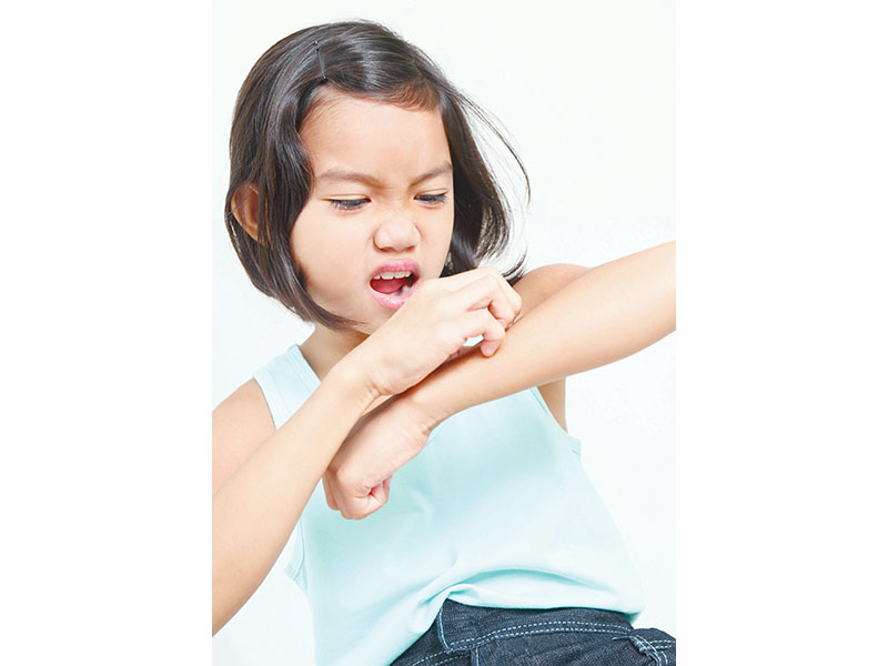 Portrait of a young asian girl scratching her arm.