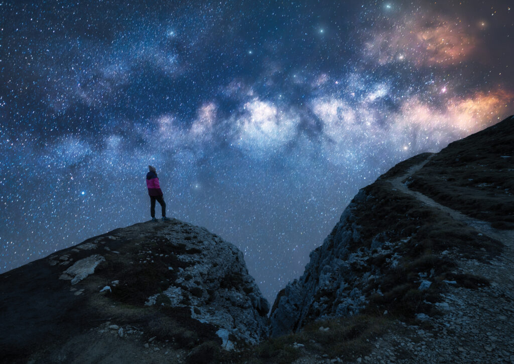 Glowing,Milky,Way,And,Woman,On,Mountain,Peak,At,Starry